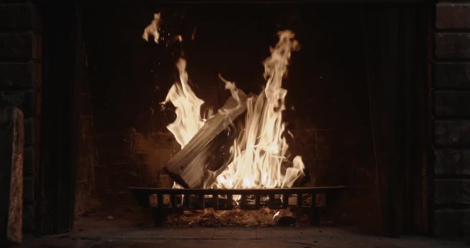 A fire is burning in a fireplace inside at night
