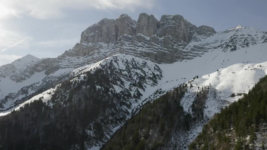 A snow covered mountain is filmed from the ground looking up