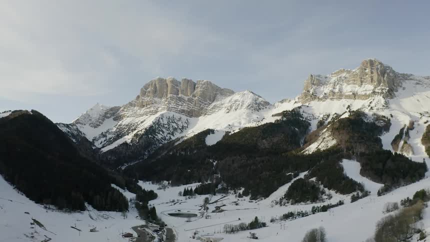 Snow is covering a valley in the mountains on a cloudy day