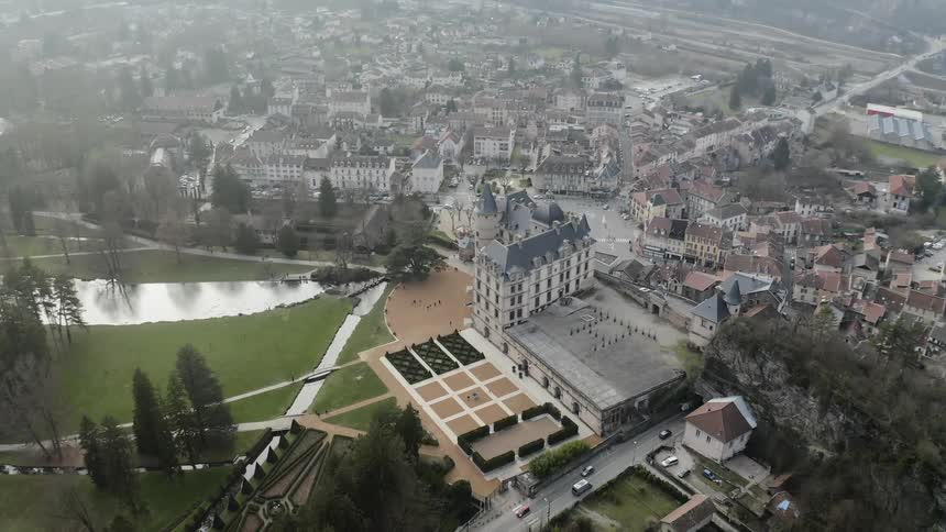 The green field has a pond near the town