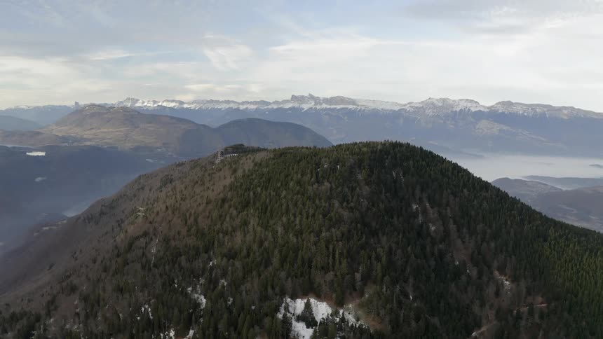 Clouds are hanging over a forested mountain during the day