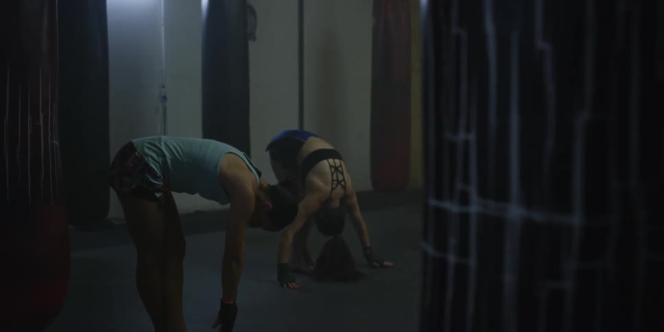 Two people stretch in a gym