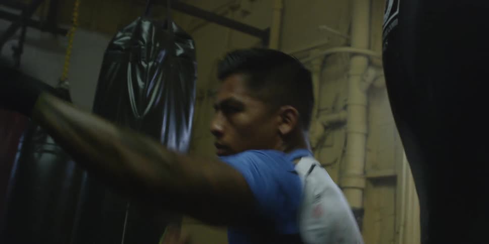 A male athlete is shadow boxing inside a gym
