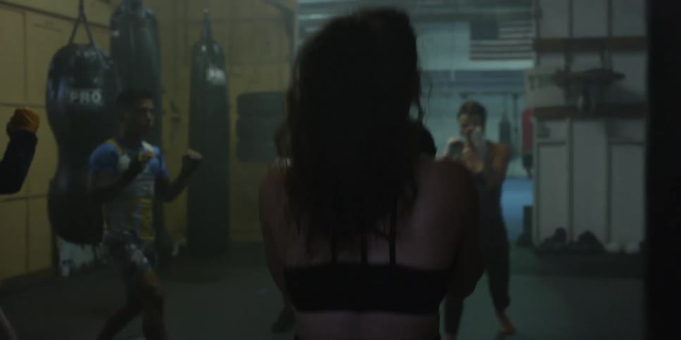 Several people stand in a circle in a gym doing lunges