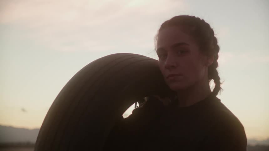 Woman holding a tire outside at sunset