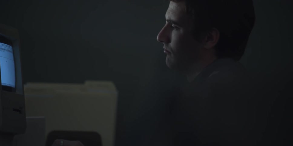 Man sitting in a dark room works on a computer