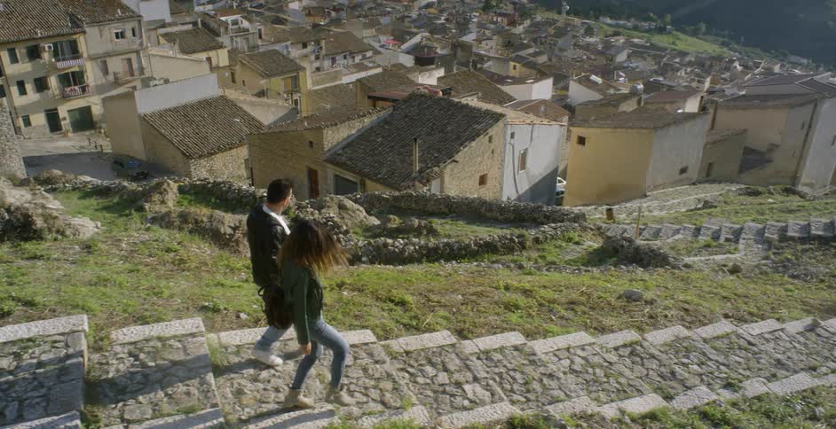 A couple holds hands as they walk down hillside steps