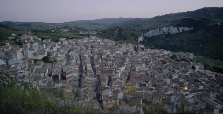 A village is sitting nestled in a mountain valley at dusk