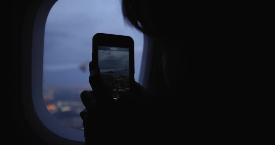 Person records with phone while sitting in an airplane as it takes off