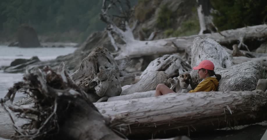 A woman leans against a fallen tree