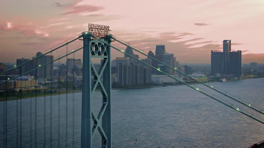 Vehicles are traveling over the ambassador bridge at dusk
