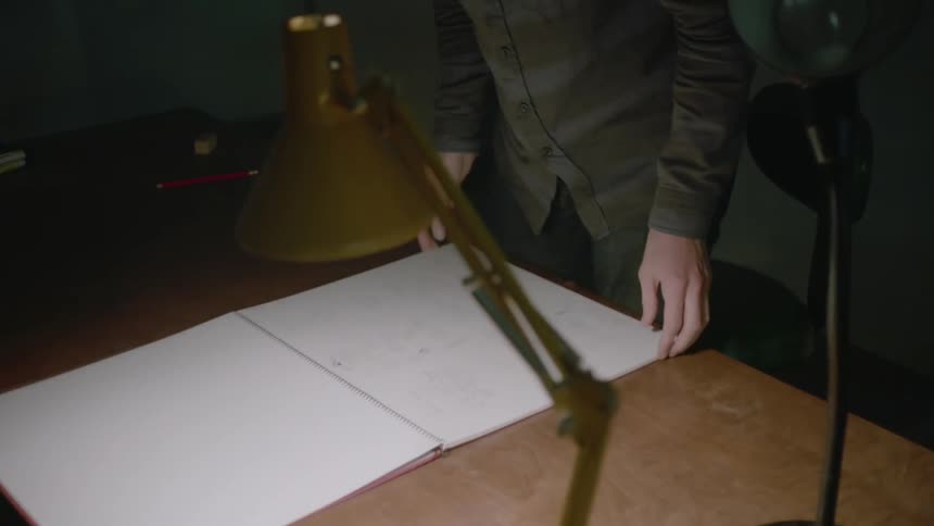 A man flips open a sketch book on a desk
