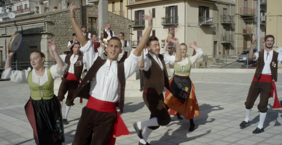 Dancers perform outside in a village