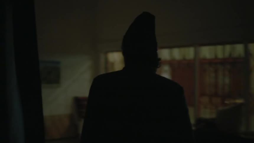 A man walks through several rooms toward a desk