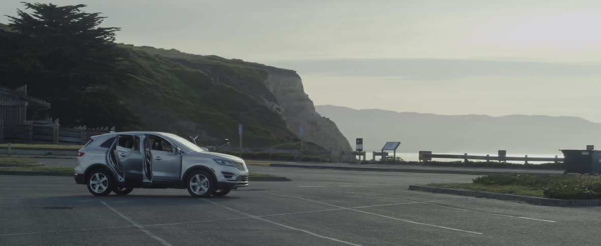 An suv in a beach parking lot with it's doors open