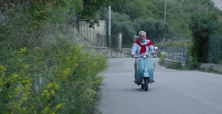 Elderly man riding a small blue motorbike