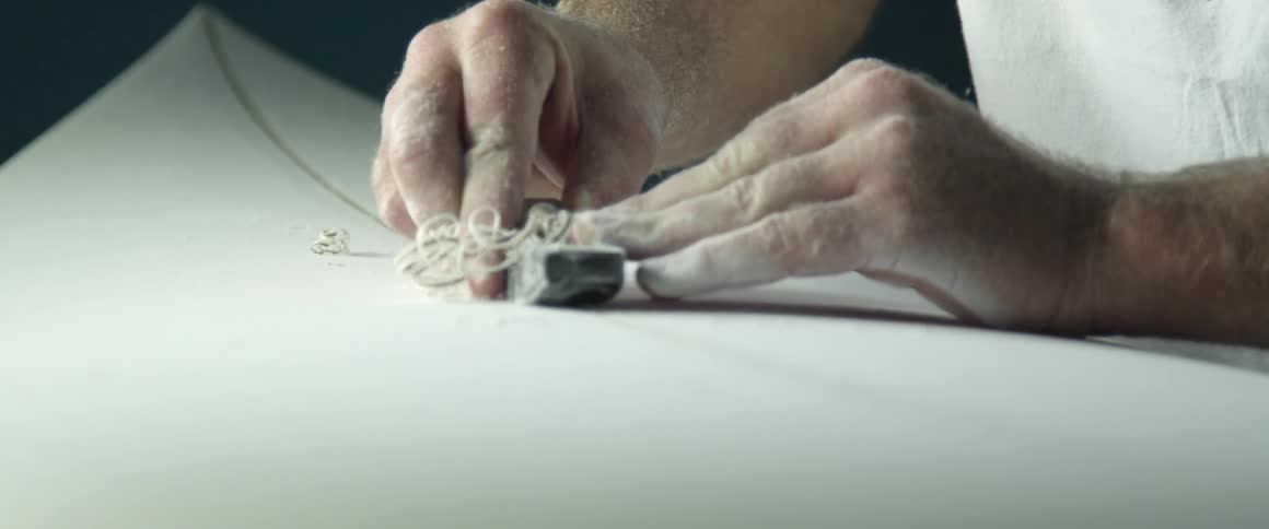 Man carving a line into a surfboard