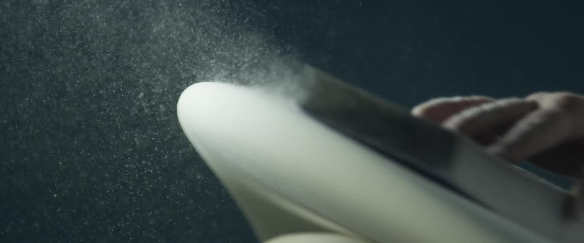 A white man sands the end of a surfboard