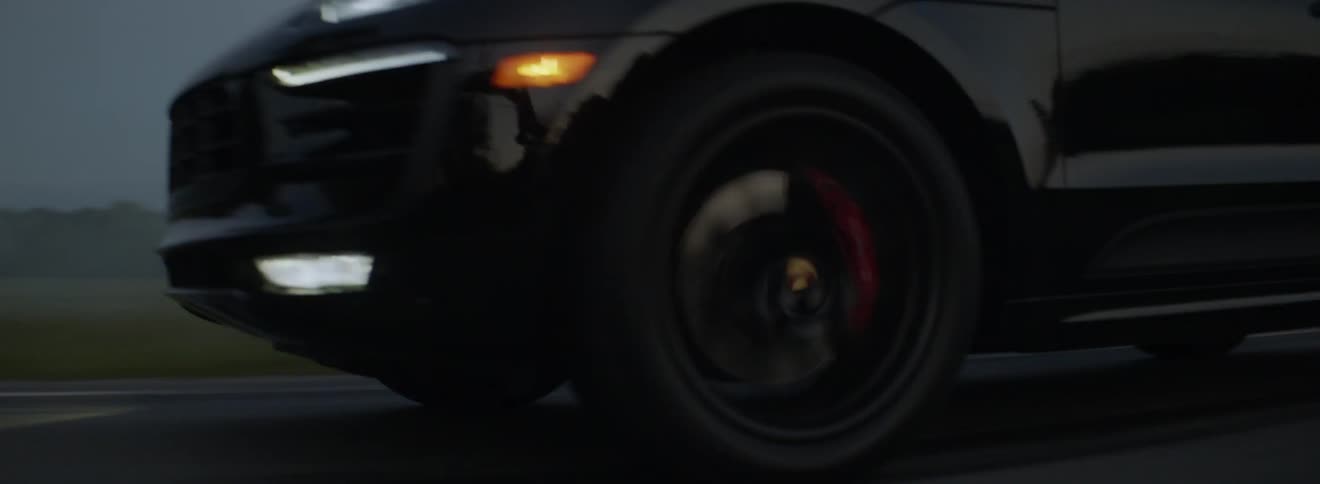A vehicle is driving on a rural road at dusk with its lights on