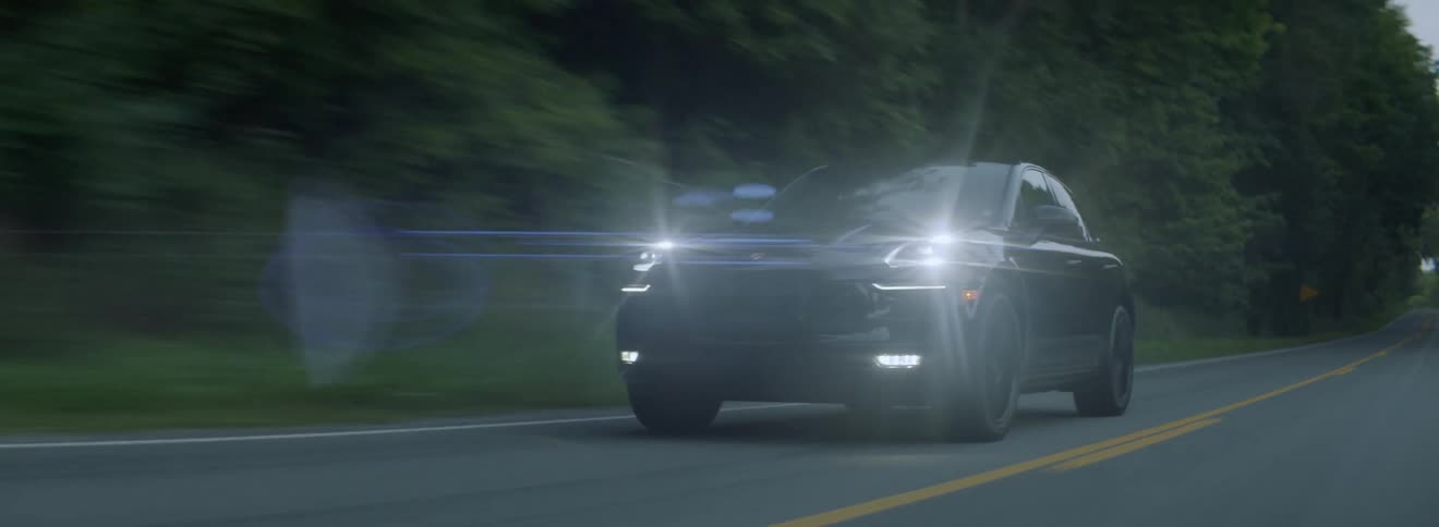 A car drives on a rural road with its headlights on