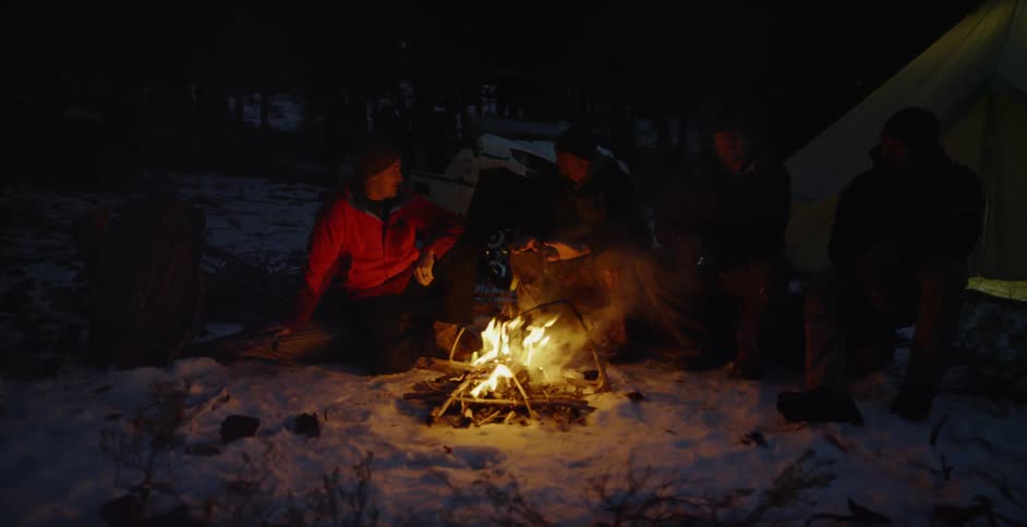 People gather around a campfire in the snow