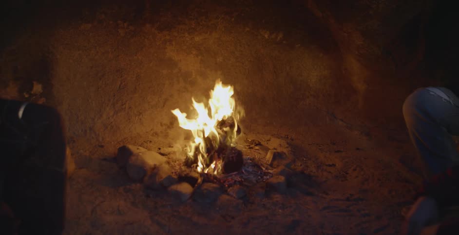 People sit around a small campfire at night