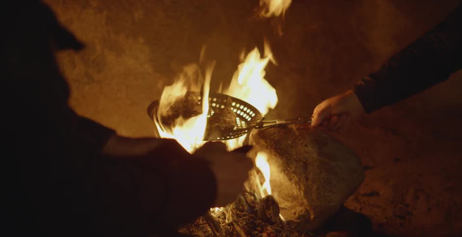 Person roasts food over an open fire