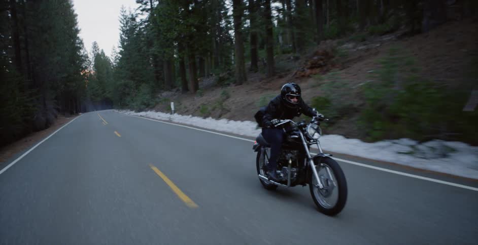 A motorcyclist rides on a forest road