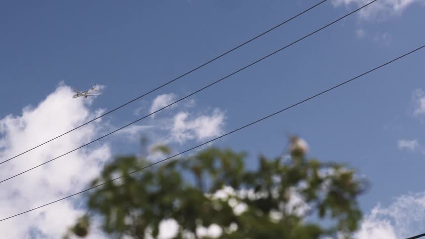 A plane flies overhead of some power lines