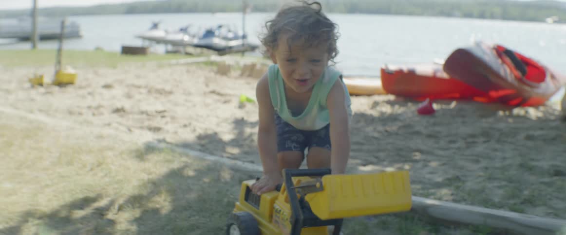 A young child plays with toys in the sand