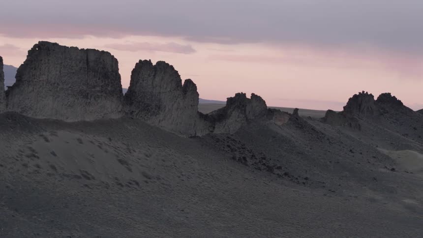 The sun sets behind rock formations in the desert