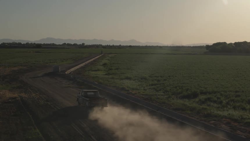 A pickup truck travels on a dirt road