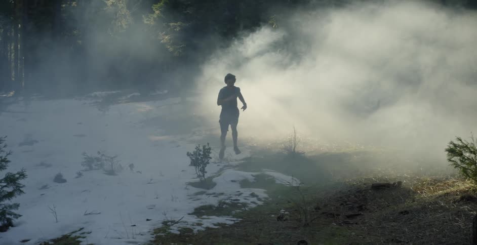 A man runs through a smoky forest