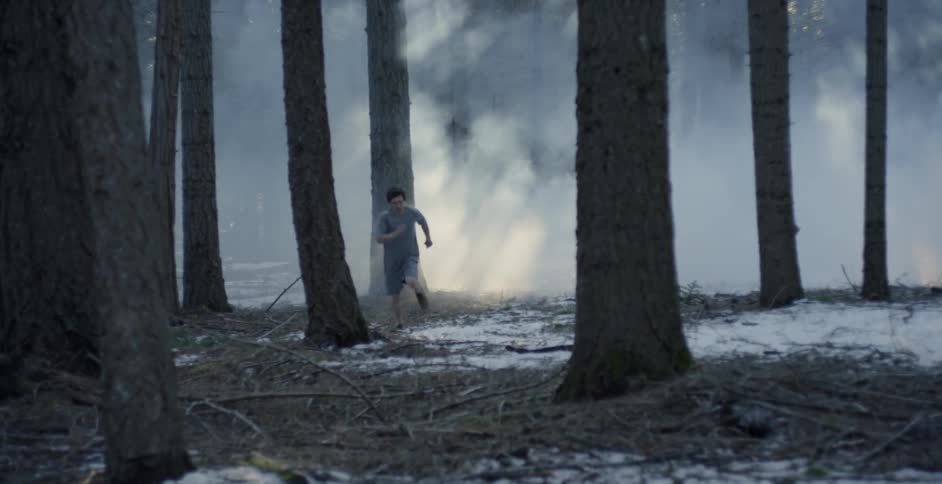 A man runs through a smoky forest