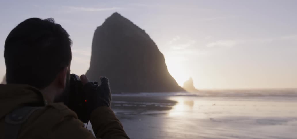 A man photographs a beach at sunset