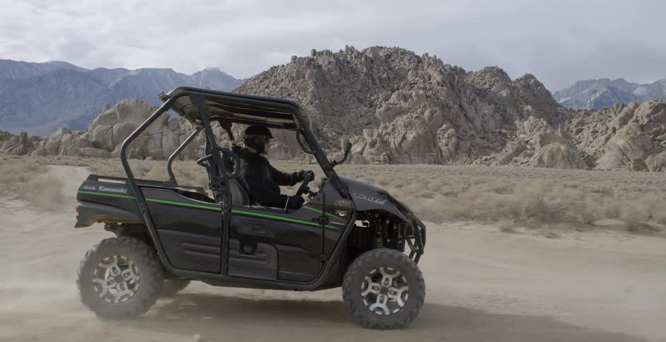 A person drives a dune buggy on a dirt road in the desert