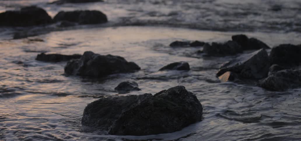 Ocean water flows around the rocks at sunset