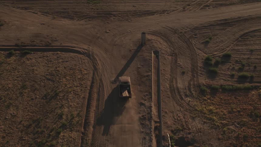 An old truck drives on a dirt road