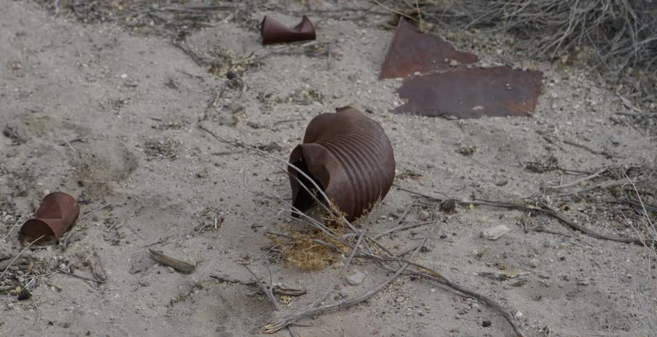Rusted trash sits in dirt
