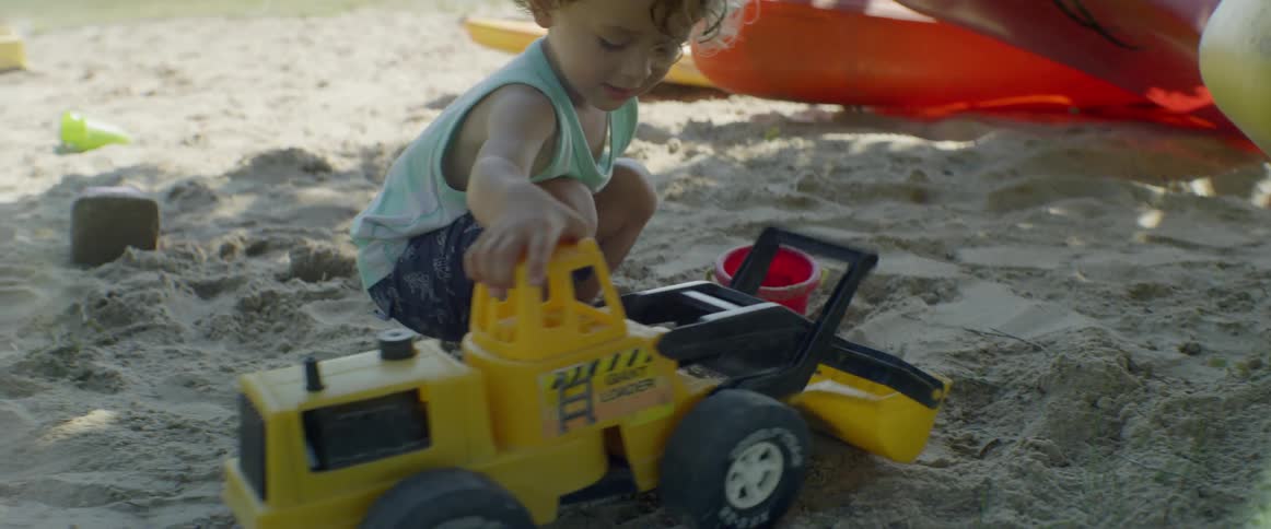 A young child plays with toys in the sand