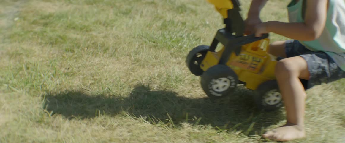 A young child plays with a toy in the grass