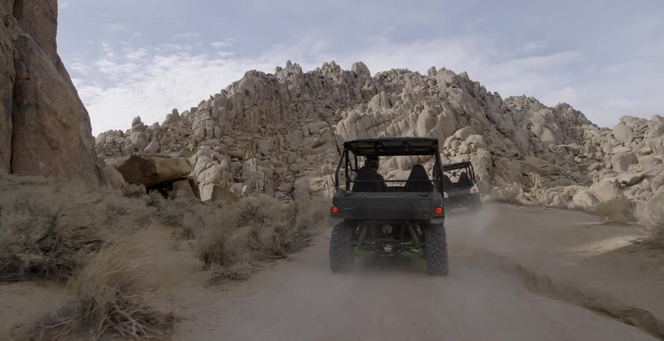 People ride in a small off road vehicle through rocky mountains