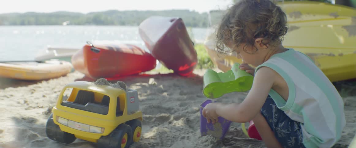 A young child plays with toys in the sand