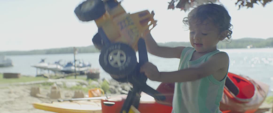 A child picks up his truck playing near the water