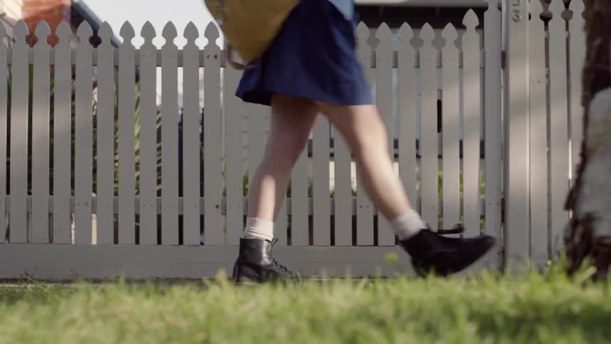 Person walking along a white picket fence