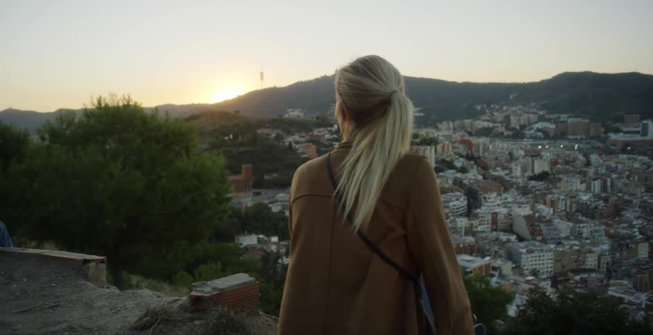 A woman sits at the edge of a cliff