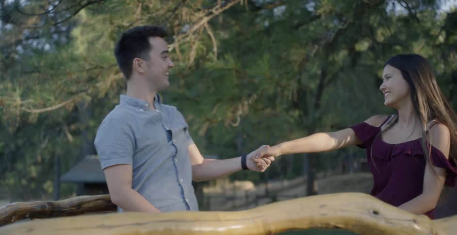 A man and woman dance outside under the trees