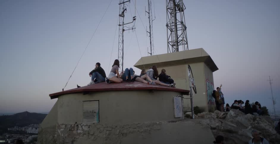 People are sitting on the roof together at sunset