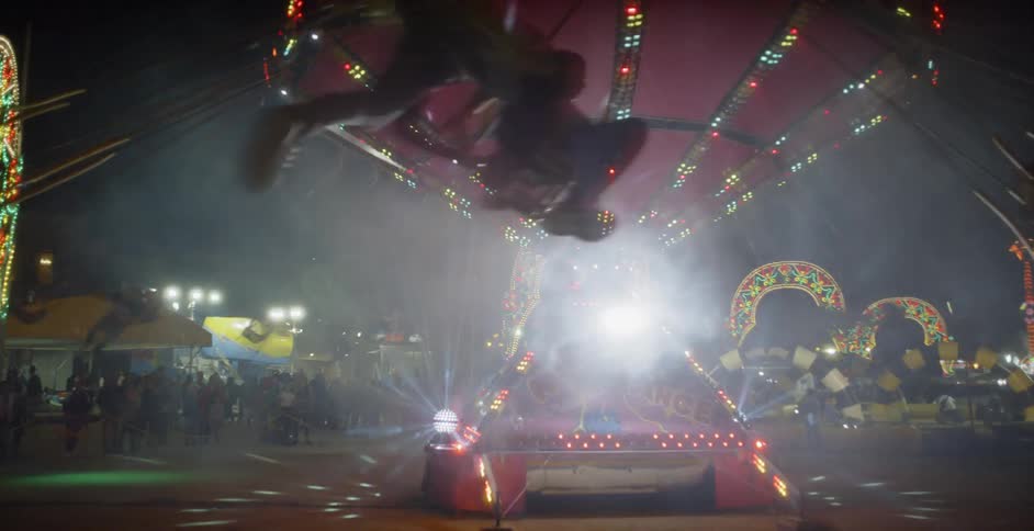 Carnival ride swings people around under a dark sky