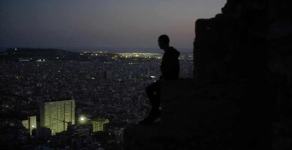Person standing on top of a building at night looks down